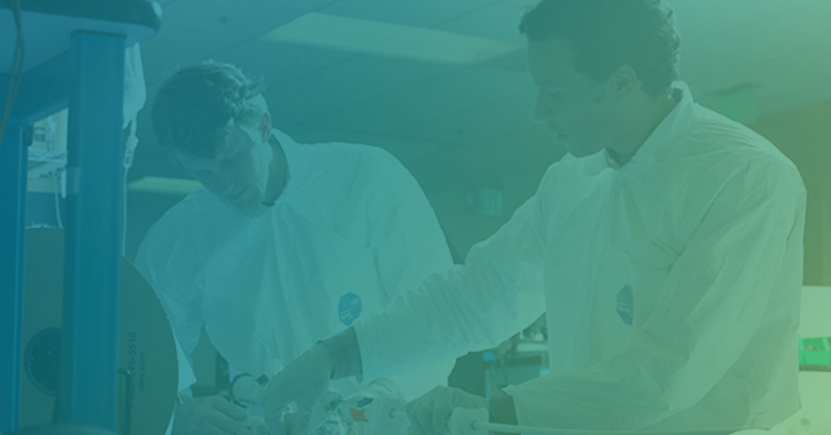 Two Foundry engineers assembling a medical device in the lab, under a teal-to-lime brand gradient