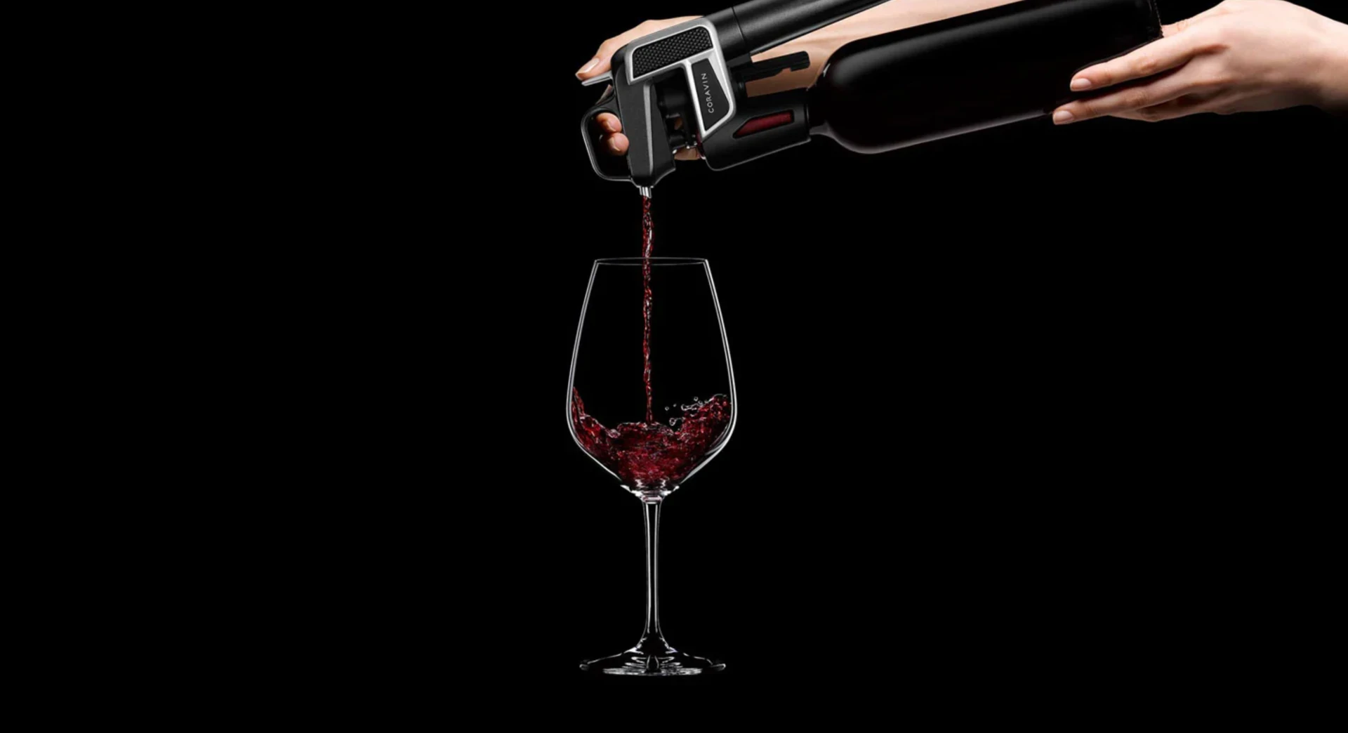 Coravin Model Two pouring red wine into a glass from an unopened bottle against black