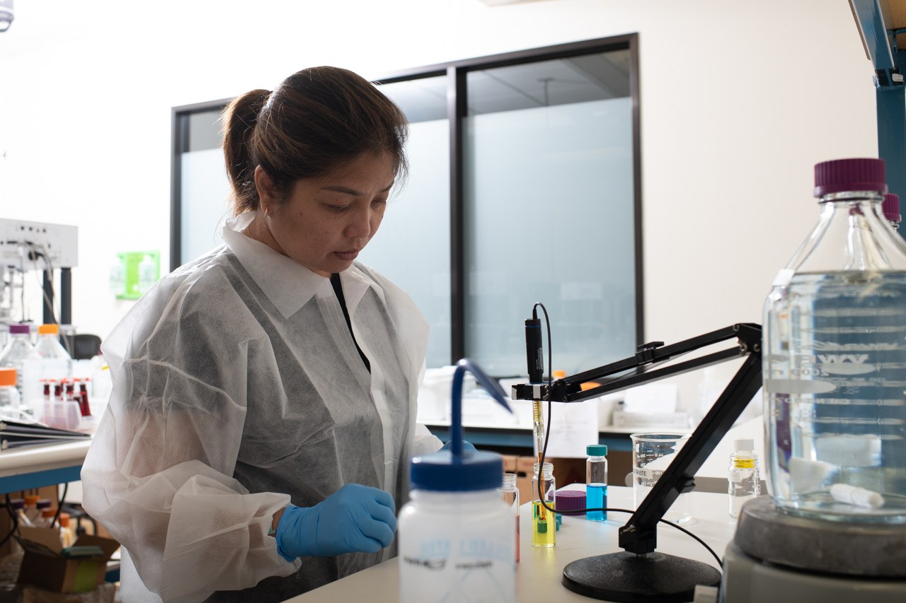 A Foundry engineer in a lab gown working at the bench