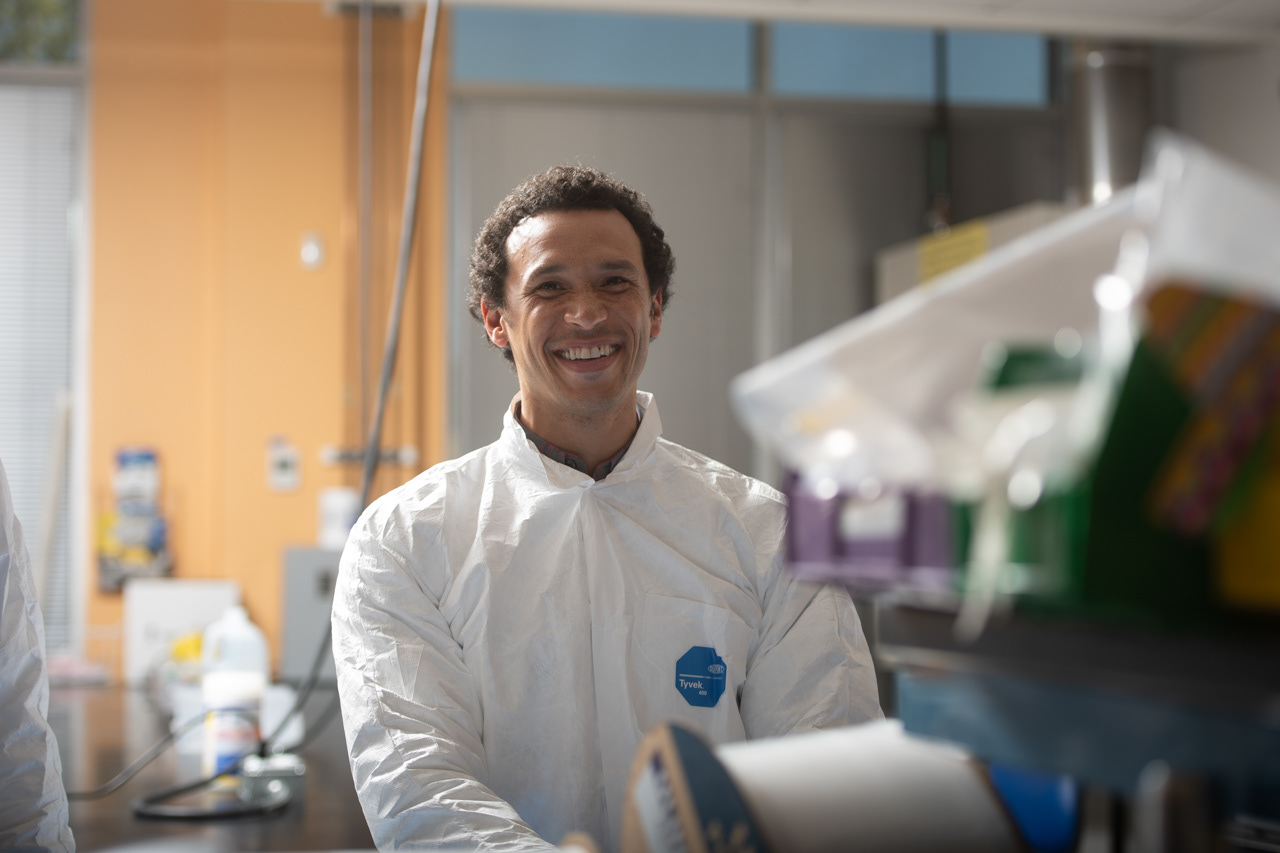 A smiling Foundry scientist in a cleanroom suit working in the lab