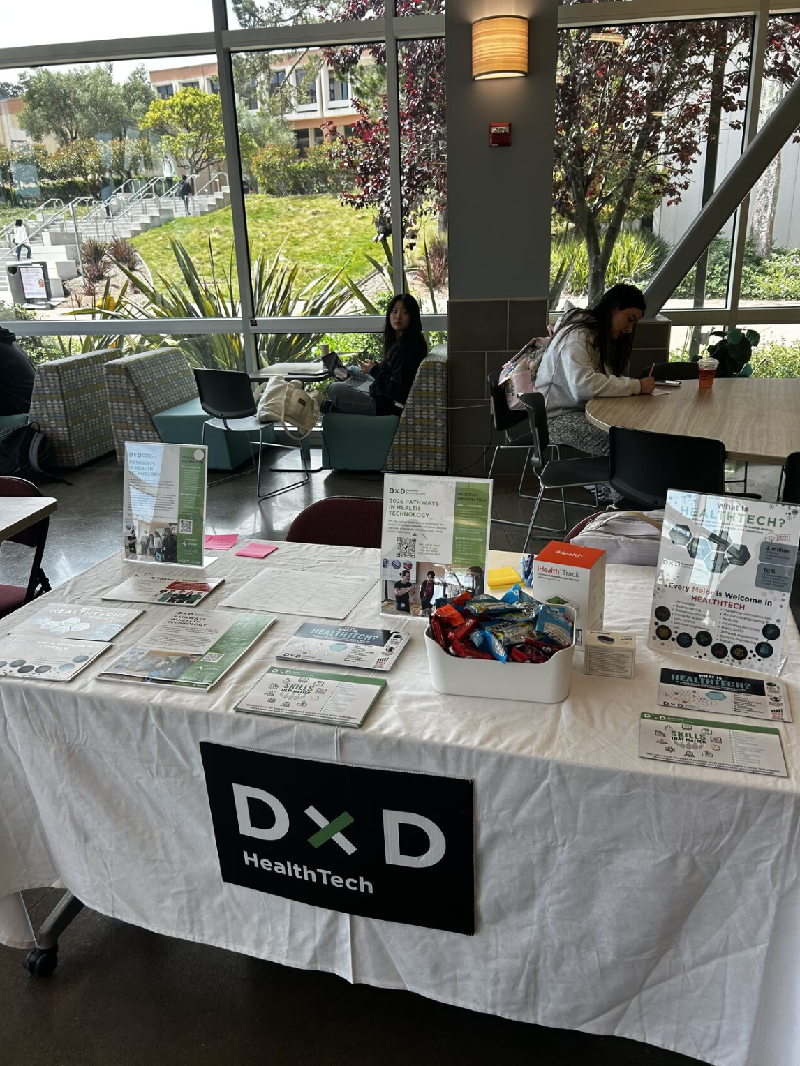 DxD HealthTech branded table cover and printed program materials at a campus outreach event