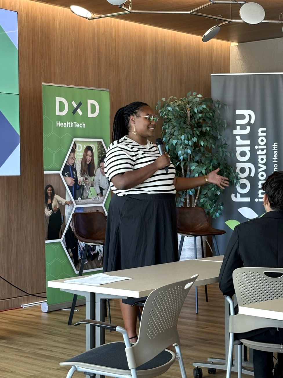 Speaker addressing an audience in front of DxD HealthTech and Fogarty Innovation banners